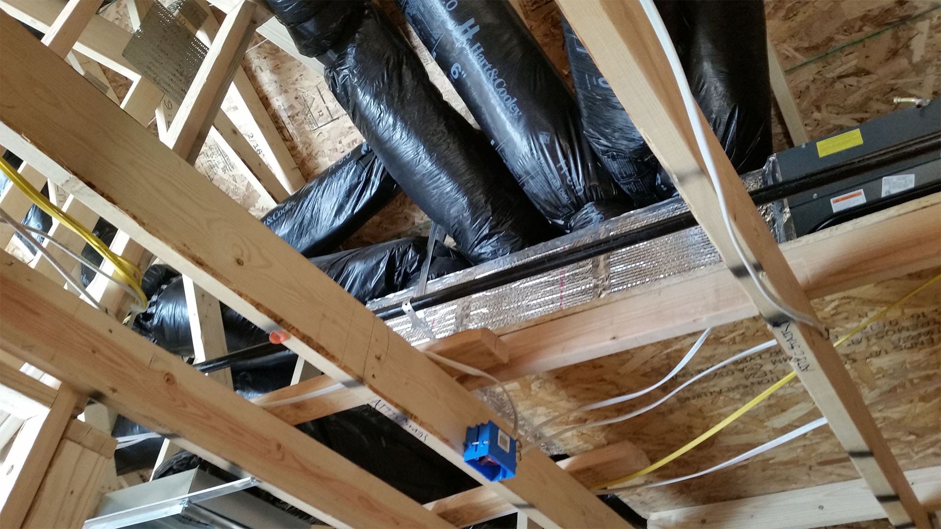 Flexible HVAC ductwork routed through the framing of a Denver home addition