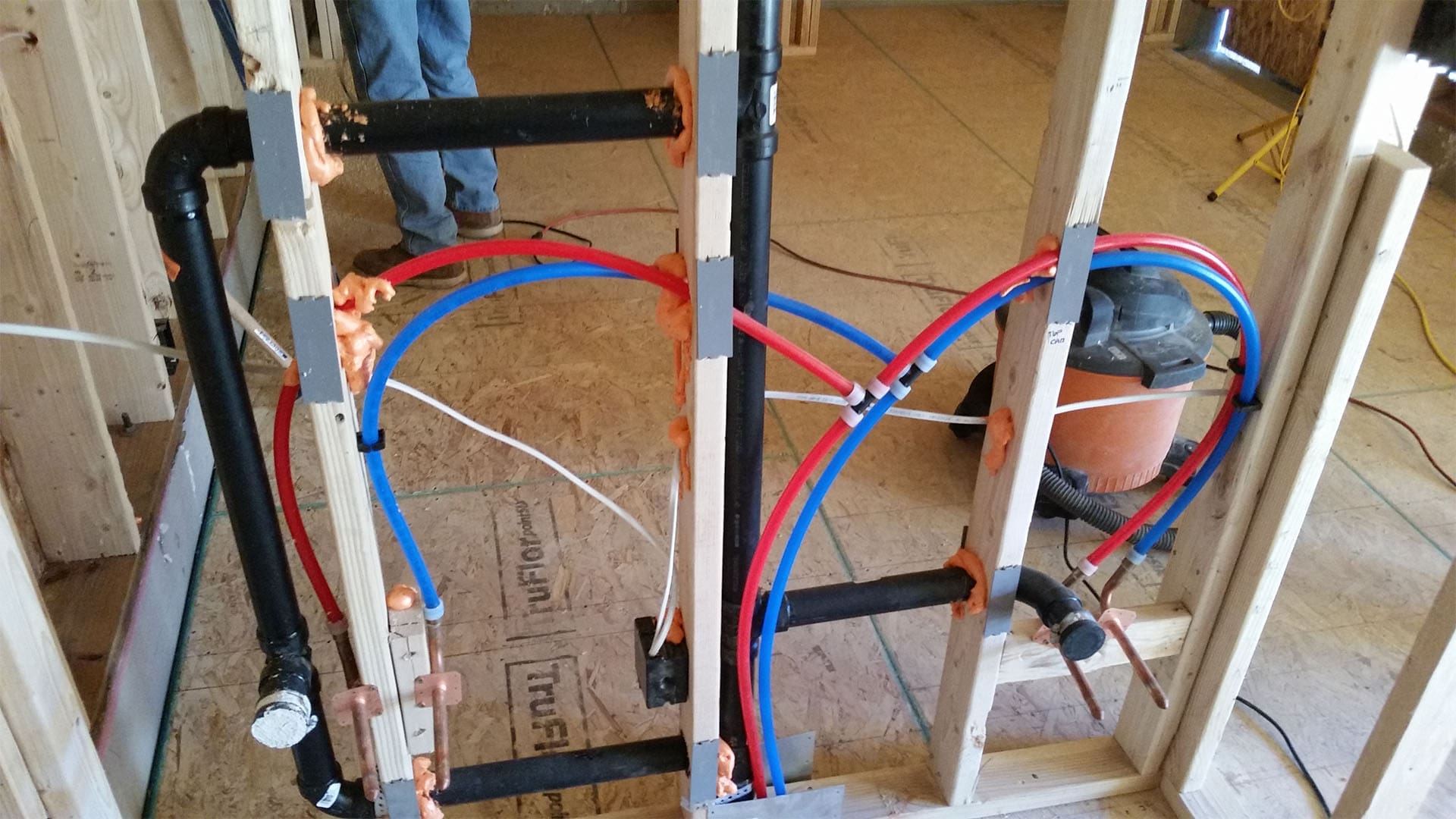 PEX water distribution manifold with red and blue supply lines in a Denver home addition