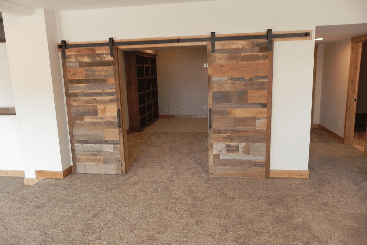 Finished basement with reclaimed barn doors and a stone feature wall, Littleton